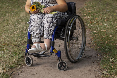 Low section of woman riding bicycle on field