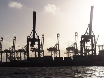 Cranes at commercial dock against sky