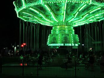 Illuminated carousel in amusement park at night