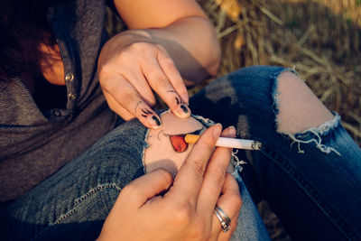 Friends creating illusion of knee smoking cigarette