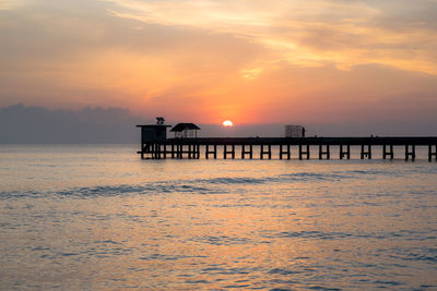 Silhouette pier over sea against sky during sunset
