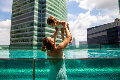 People in swimming pool against sky in city