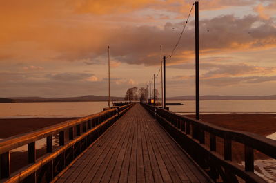 Pier on sea against cloudy sky