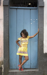 Portrait of woman standing against door