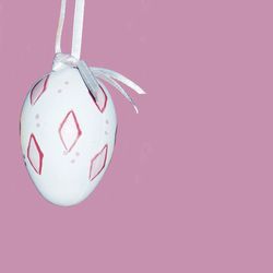 Easter egg hanging against pink wall