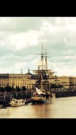 Boats in harbor against cloudy sky