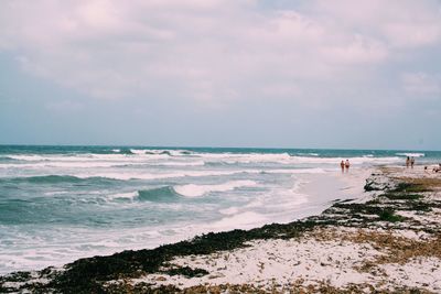 Distance shot of people walking on beach