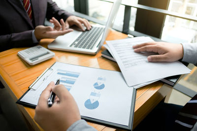 Midsection of man using laptop on table