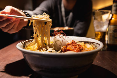 Midsection of person holding ice cream in bowl on table