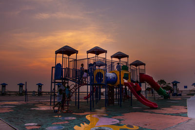 Children playing on slide against cloudy sky