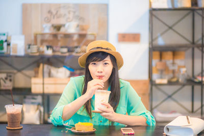 Portrait of young woman sitting on table at cafe