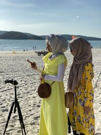 Two people looking at mobile phone at photographying nearby the seaside