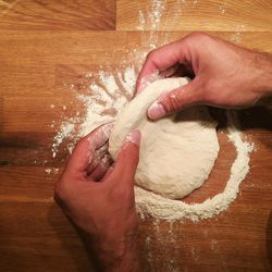 Cropped hand of man preparing dough at table