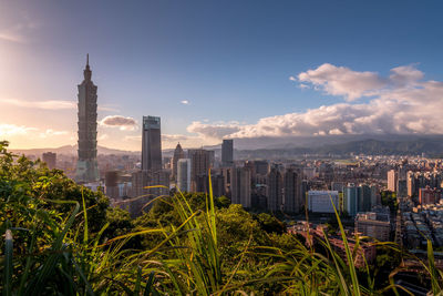 Aerial view of buildings in city against cloudy sky