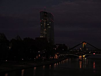 Illuminated bridge over river against sky at night