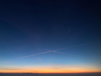 Low angle view of vapor trails in sky during sunset