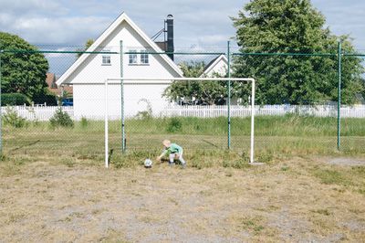 Full length of boy playing soccer on field against sky