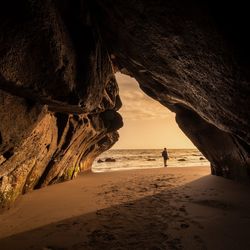 Man walking in cave at beach
