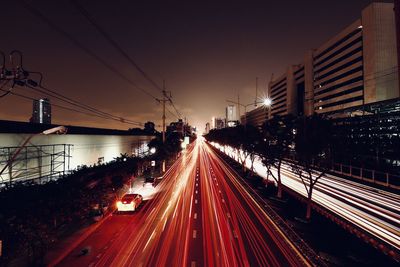 Light trails on road in city against sky at night