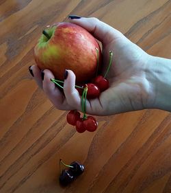 High angle view of hand holding apple on table
