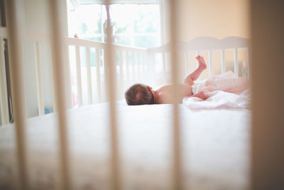 Baby girl lying down in crib at home