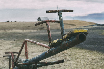 Close-up of machine part on field against sky