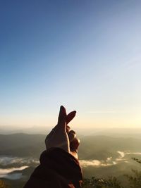 Person on mountain against sky during sunset