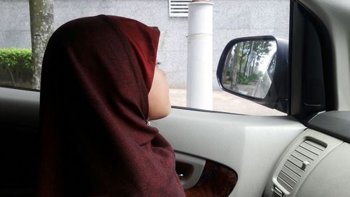 Close-up of girl wearing hijab while sitting in car