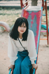 Portrait of young woman sitting on land