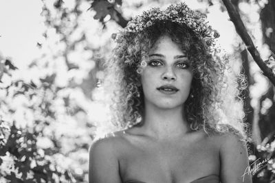 Portrait of beautiful young woman against trees