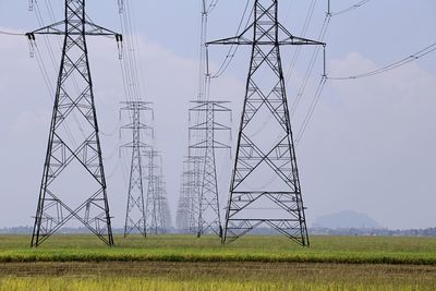Electricity pylon on field against sky