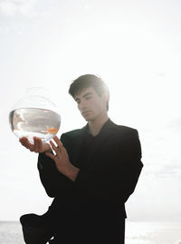 Reflection of man drinking glass on water against sky