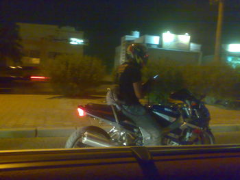 Man riding motorcycle on illuminated street at night