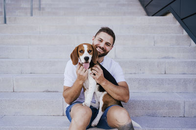 Portrait of man with dog sitting on staircase