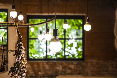 Low angle view of illuminated light bulb hanging from ceiling