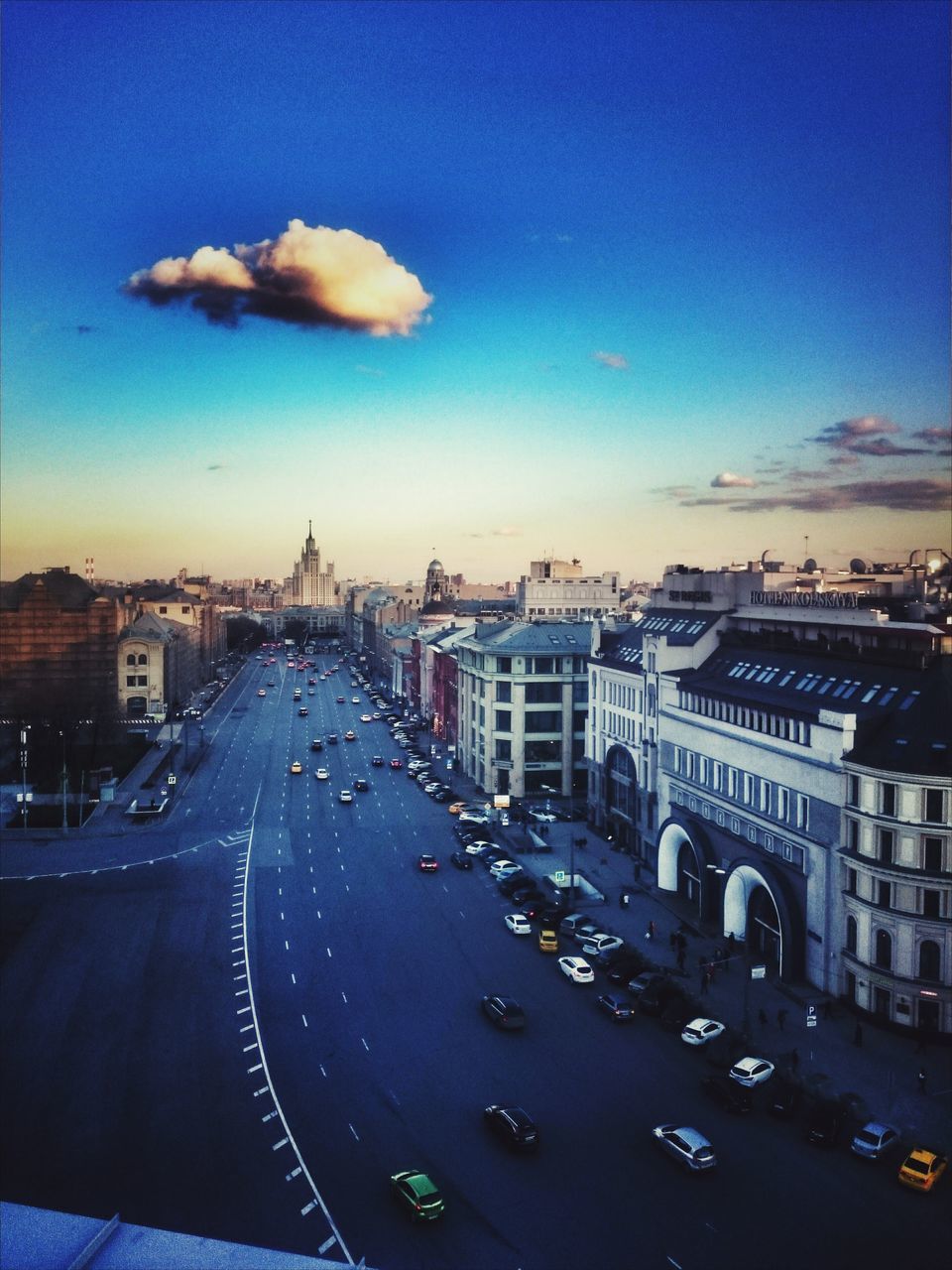 building exterior, city, architecture, built structure, transportation, cityscape, blue, car, sky, road, street, mode of transport, city life, land vehicle, high angle view, illuminated, residential district, dusk, city street, residential structure