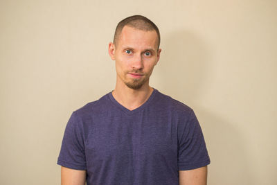 Portrait of young man standing against wall