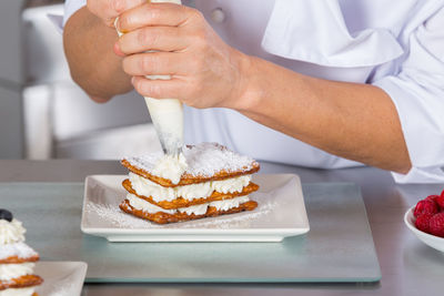 Midsection of man preparing cake on table