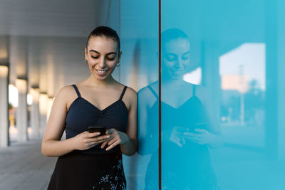 Beautiful woman using mobile phone by modern building