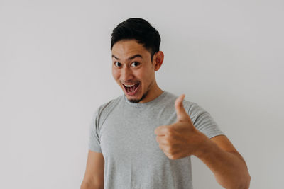 Portrait of young man standing against white background