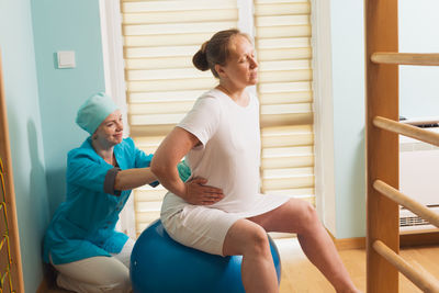 Side view of woman sitting on railing