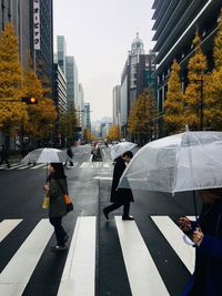 People crossing road in city during rainy season