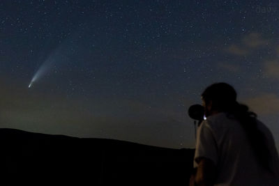 Rear view of silhouette man against sky at night