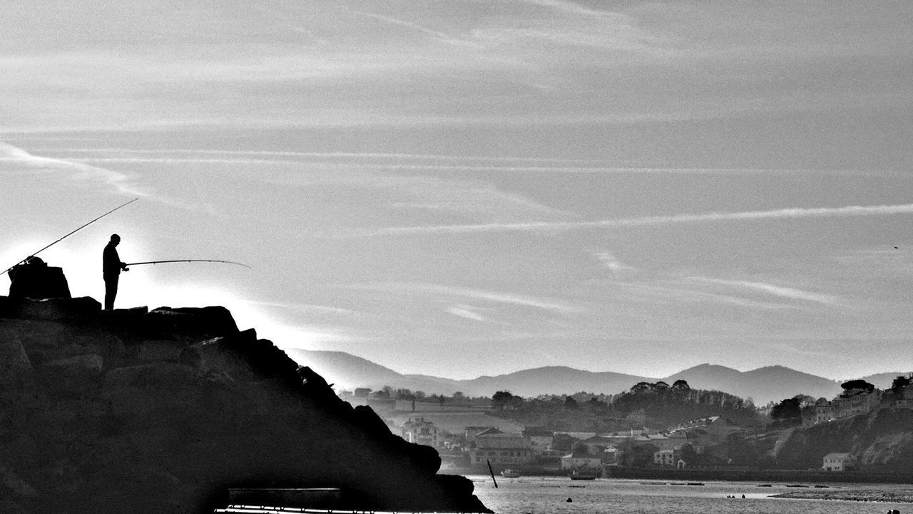 SILHOUETTE MAN STANDING IN MOUNTAINS AGAINST SKY