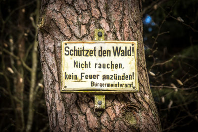 Close-up of warning sign on tree trunk