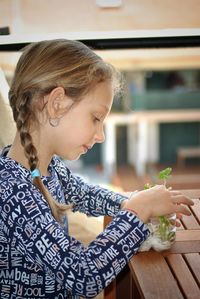 Girl looking away while sitting on table