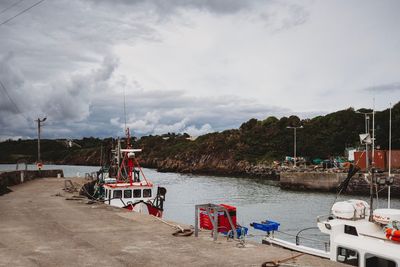 Boats moored at harbor against sky