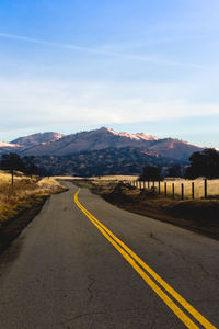 Road leading towards mountain against sky