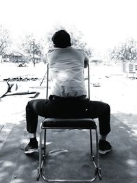 Rear view of man sitting on bench in snow
