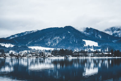 Scenic view of lake by snowcapped mountains against sky